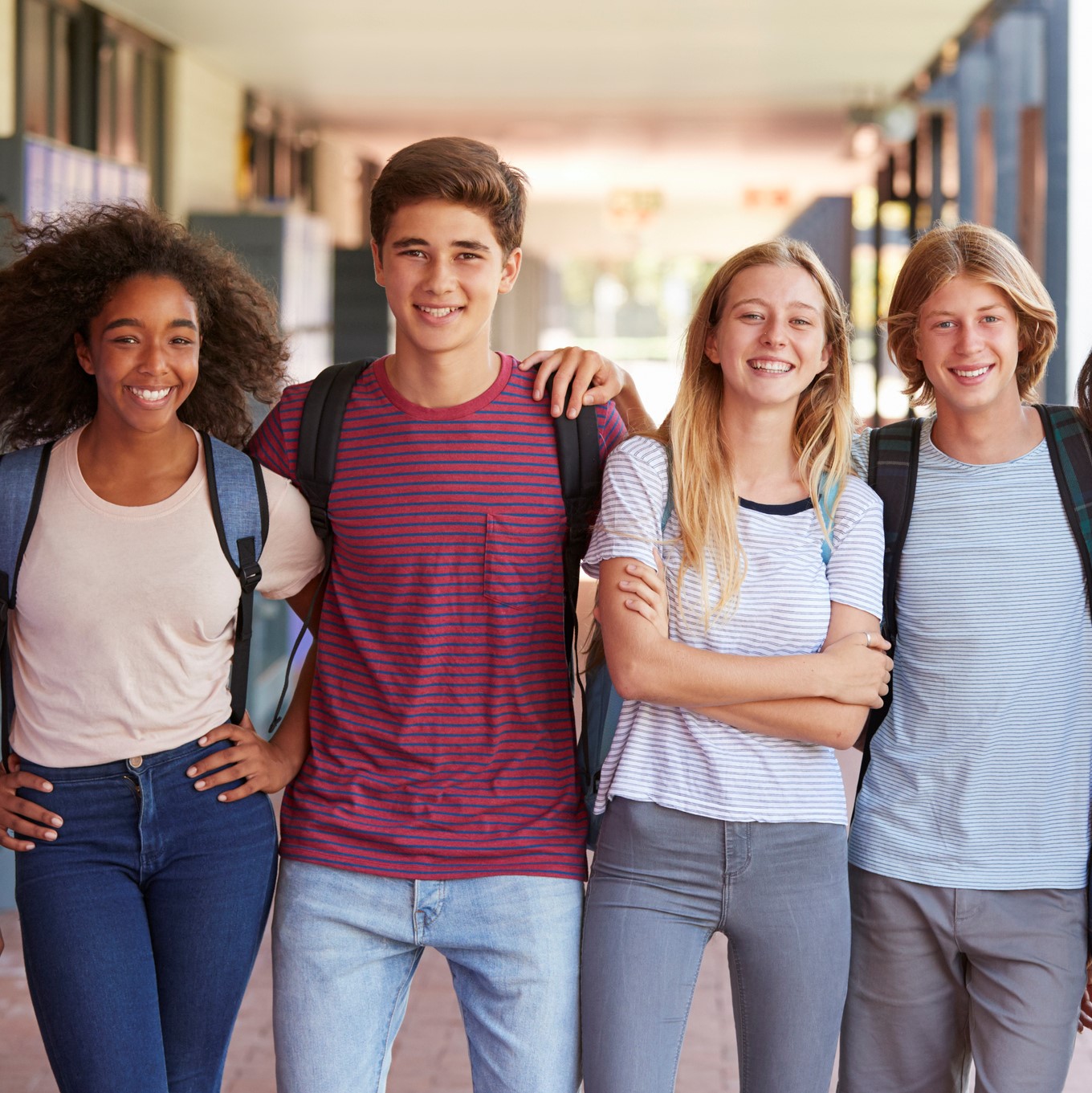 Teenage classmates standing in high school hallway